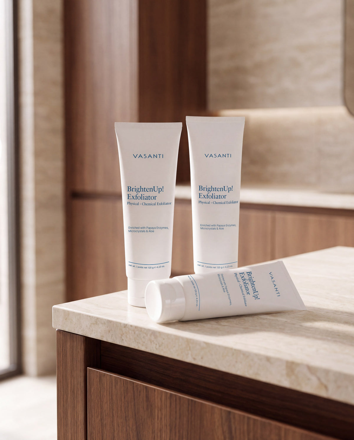 Three BrightenUp! Exfoliator tubes on a warm stone counter