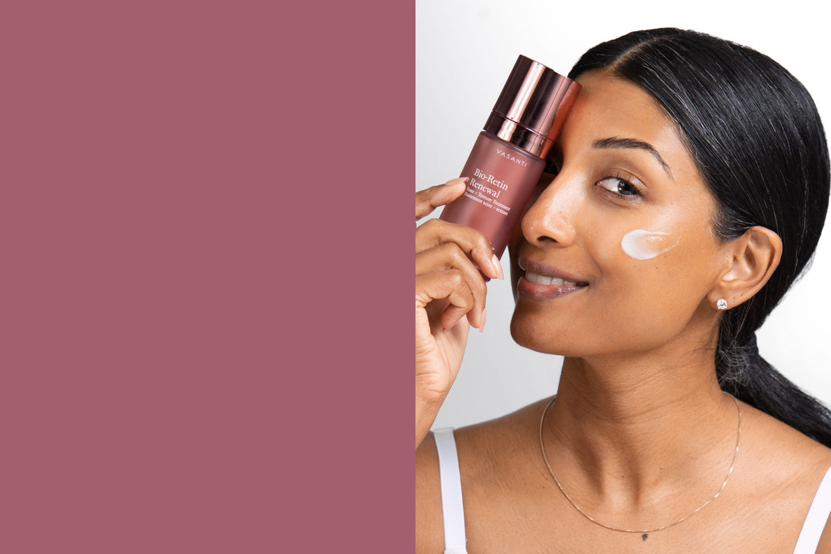 Woman holding Bio-Retin Renewal over one eye, smiling, a swipe of cream on her cheek