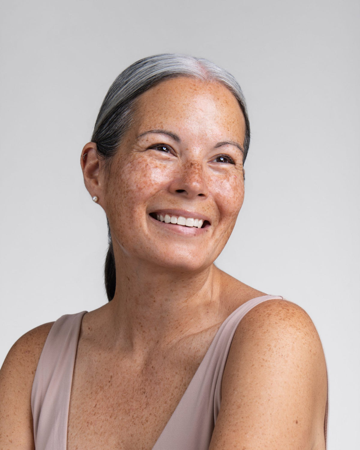 Woman with freckled skin and silver hair, smiling
