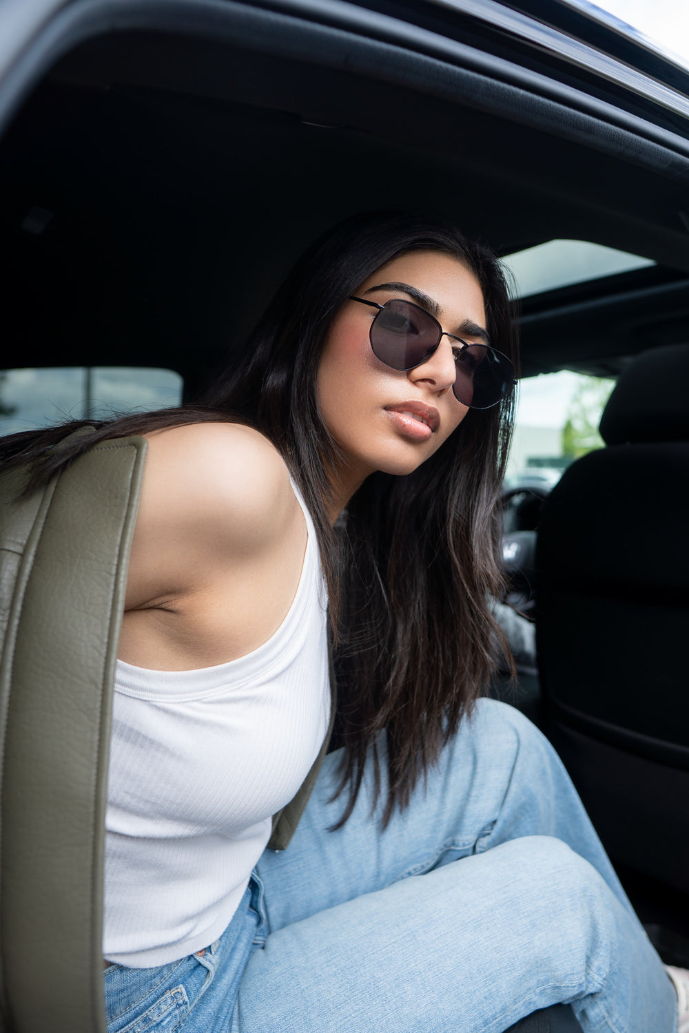 Penchée hors d'une portière, lunettes de soleil sur le nez